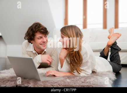 Couple using laptop together on rug Stock Photo