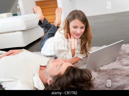 Couple using laptop together on rug Stock Photo