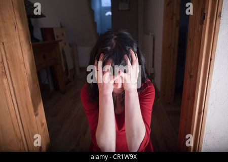 Woman clutching her head in doorway Stock Photo
