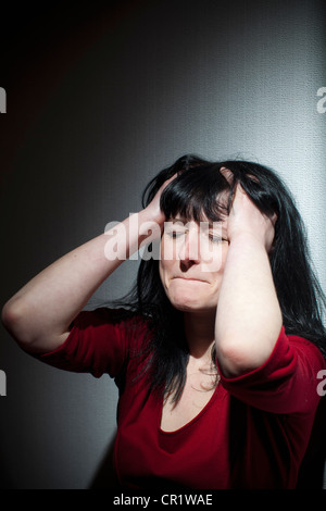 Crying woman clutching her head Stock Photo