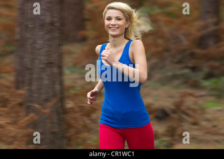 Smiling woman running in woods