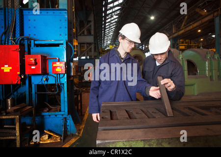 Workers examining metal in steel forge Stock Photo