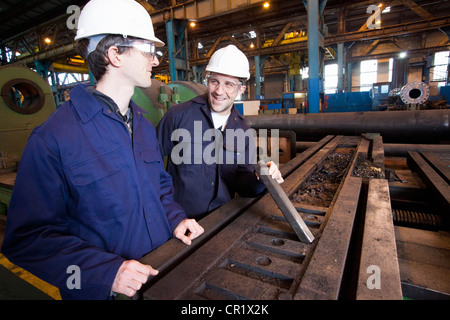 Workers examining metal in steel forge Stock Photo