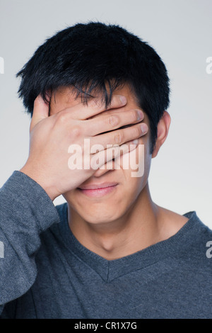 Studio portrait of young man covering eyes Stock Photo