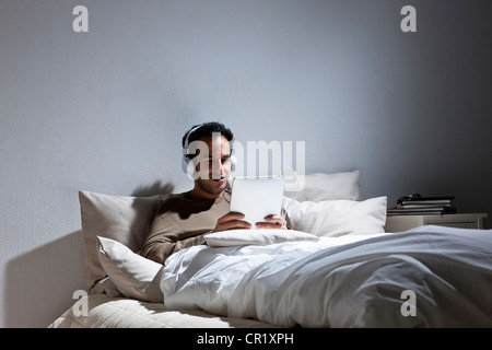 Man using tablet computer in bed Stock Photo