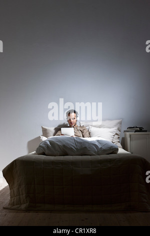 Man using tablet computer in bed Stock Photo