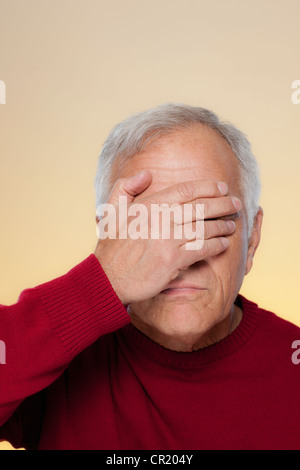 Studio shot of senior man covering eyes Stock Photo
