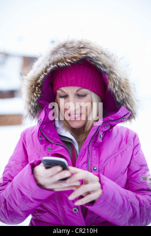 Woman using cell phone in snow Stock Photo