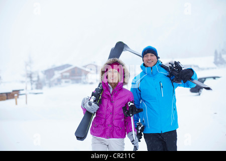 Couple carrying skis and poles in snow Stock Photo