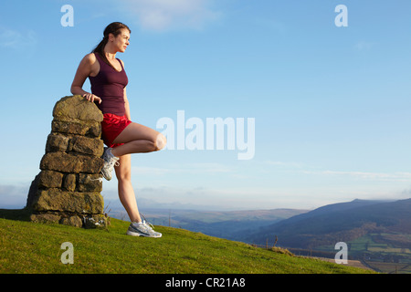 Runner leaning against rock wall Stock Photo