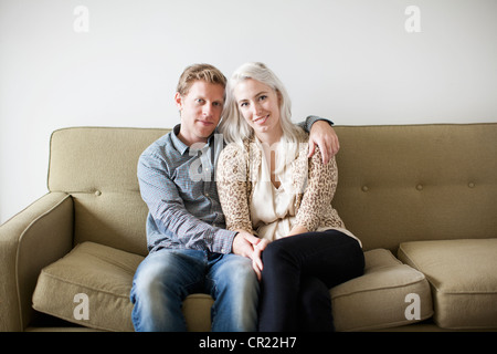 Portrait of happy young couple sitting on sofa Stock Photo