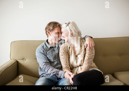 Happy young couple embracing on sofa Stock Photo