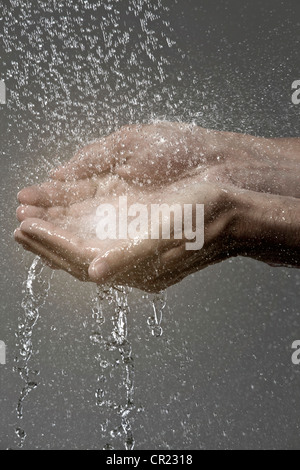 Woman catching water in cupped hands Stock Photo