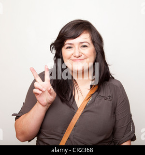 Studio Shot of young woman making Peace Sign Stock Photo