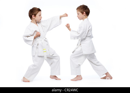 Little twins in uniform practicing judo, isolated on white Stock Photo