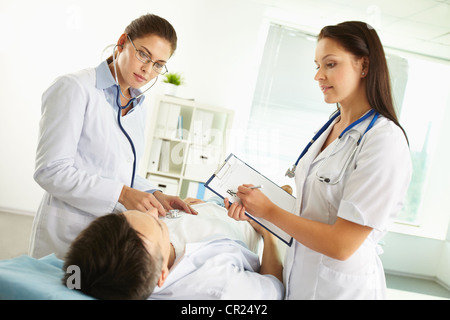 Female doctors examining the patient and listening attentively to his complaints Stock Photo
