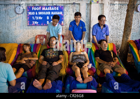 Foreign tourists receive massage in public on Soi Rambuttri, Bangkok, Thailand. Stock Photo