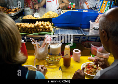 Foreign tourists eating pad thai outdoors on Soi Rambuttri near Khao San Road, Bangkok, Thailand. Stock Photo