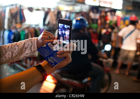 Asian tourists take a photo of themselves with an iPhone 4s on Khao San Road, Bangkok, Thailand. Stock Photo