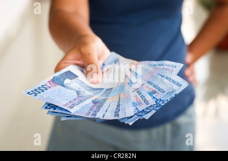 close up of a stack of indonesian rupiah, handed out by a woman. Stock Photo