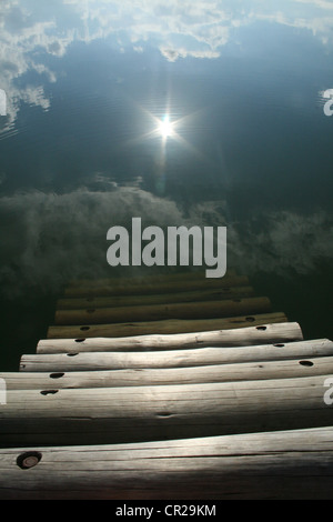 Wooden steps leading to the sun reflected in a still pool, Drakensburg Mountains, South Africa. Stock Photo