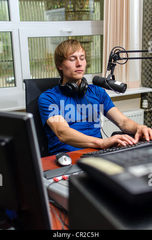 Dj working in front of a microphone on the radio Stock Photo