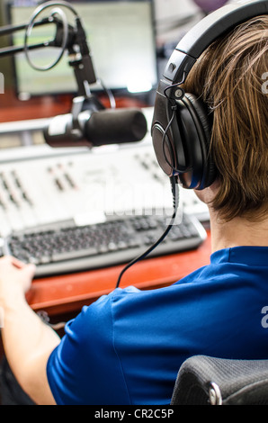 Dj working in front of a microphone on the radio, from the back Stock Photo