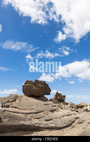 Boulders on barren rock and blue sky with clouds at Castlepoint, Wairarapa coast, Wellington, New Zealand, Oceania Stock Photo