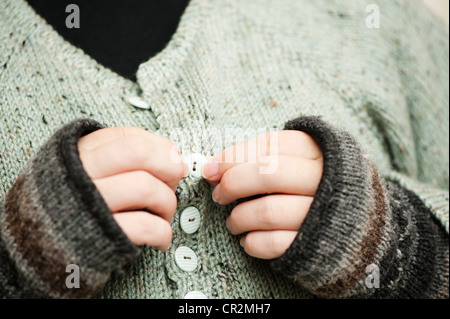 Abstract close up of man doing up buttons on a hand-knitted jumper Stock Photo