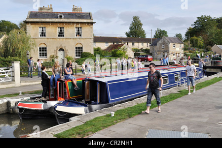 Two narrowboats negotiate Bradford on Avon lock on the Kennet and Avon Canal, while a group of interested spectators look on. Stock Photo