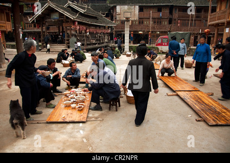 Funeral food party in front of a basketball court and a small 'Wind and Rain' bridge, Zhaoxing Dong Village, China Stock Photo