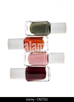 Nail polish bottles of various colors stacked isolated on white background Stock Photo