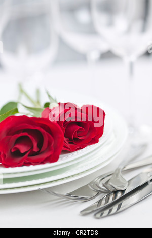 Romantic table setting for two with roses plates and cutlery Stock Photo