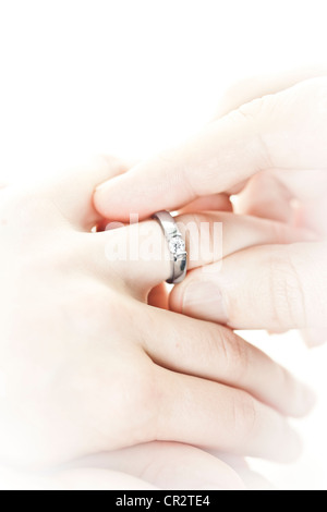 Closeup of hands placing engagement ring on finger Stock Photo