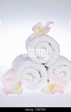 White rolled up spa towels with orchids flowers Stock Photo