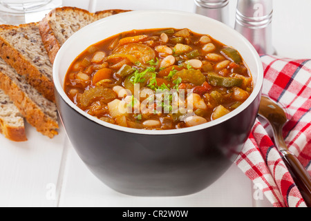 A bowl of vegetable soup on a table with bread. Stock Photo