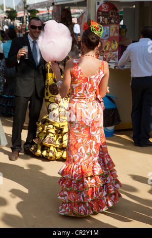 Young woman wearing a flamenco dress, with candyfloss, at the 'Feria de Abril' April Fair in Seville, Andalucia, Spain, Europe Stock Photo