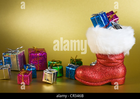Red Santa boot and gifts on gold background Stock Photo