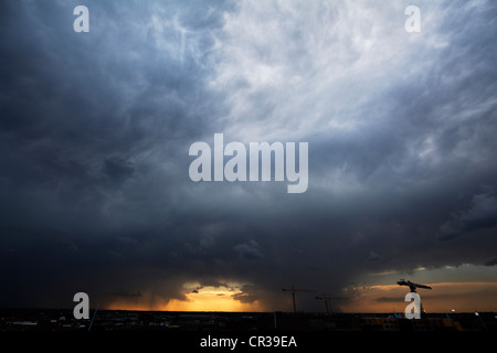 Two areas of very heavy rainfall in a thunderstorm, showing tower cranes and mammatus clouds. Stock Photo
