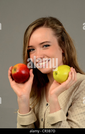 Young woman with two apples, one red and one green, in her hands Stock Photo