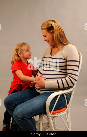 Pregnant mother sitting with her 5 years old daughter Stock Photo