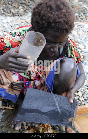 Woman panning gold in the polluted Jaba river flowing from Panguna copper mine. Autonomous Region of Bougainville, PNG Stock Photo