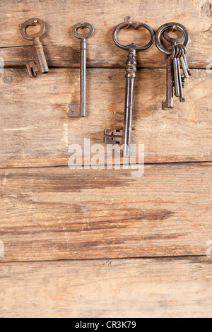 Keyring and rusty keys hanging on a wooden background Stock Photo