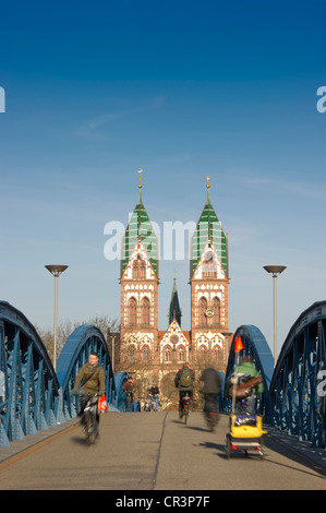 Cyclists on the Blaue Bruecke bridge, with motion blur, Stuehlinger Kirche church at the back, Freiburg im Breisgau Stock Photo