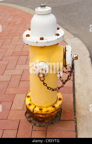 Old yellow fire hydrant on the sidewalk Stock Photo