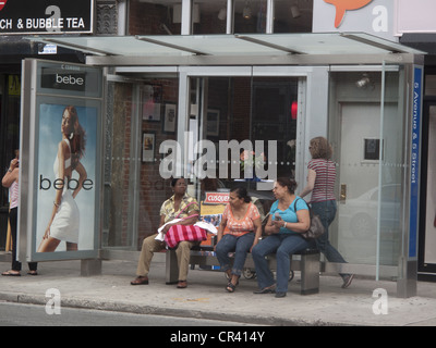 Women at a bus stop on 5th Avenue in Park Slope Brooklyn. Stock Photo