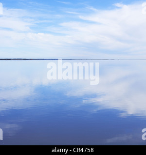 Smooth and tranquil water reflecting clouds. Stock Photo