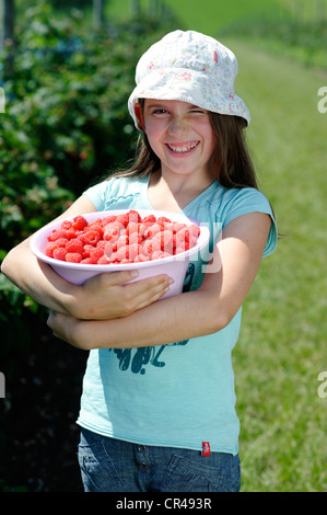 Girl on a raspberry farm, with a bowl full of freshly picked raspberries, Bavaria, Germany, Europe Stock Photo