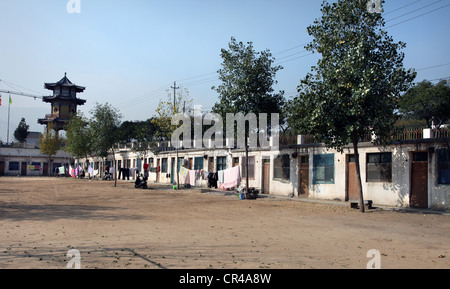It's a photo of a small village in line near a school for people to live in. We can see a Chinese temple tower in the background Stock Photo