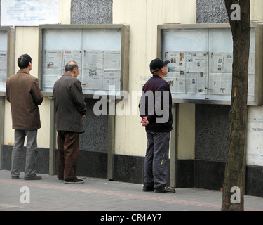 Reading the government newspaper on Fahuazhen Road in Shanghai Stock Photo